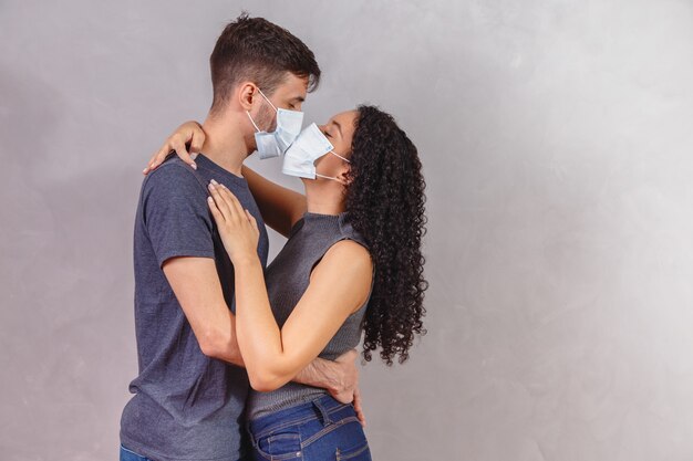 Casal de jovens da geração Y usando máscaras protetoras e se beijando, o vírus espalhou o conceito de prevenção e pessoas.