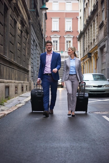 Foto casal de jovens empresários entrando no hotel da cidade, procurando quarto, segurando malas enquanto caminhava na rua