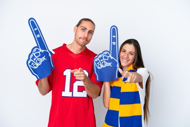 Casal de jovens fãs de esportes isolado no fundo branco aponta o dedo para você com uma expressão confiante