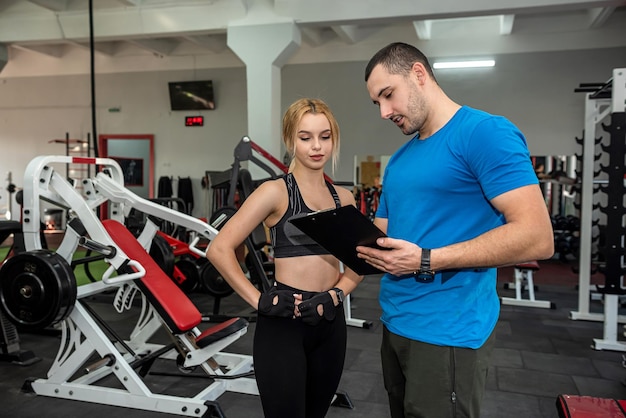 Casal de jovens magros malham juntos na academia de ginástica