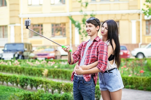 Casal de jovens turistas felizes tirando uma selfie com smartphone no monopé na cidade que o homem está