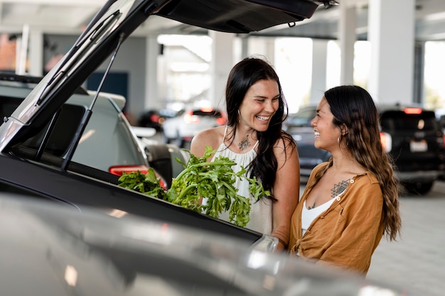 Casal de lésbicas fazendo compras, colocando coisas no porta-malas do carro