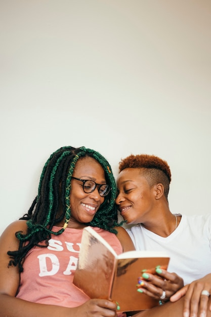 Casal de lésbicas feliz lendo um livro