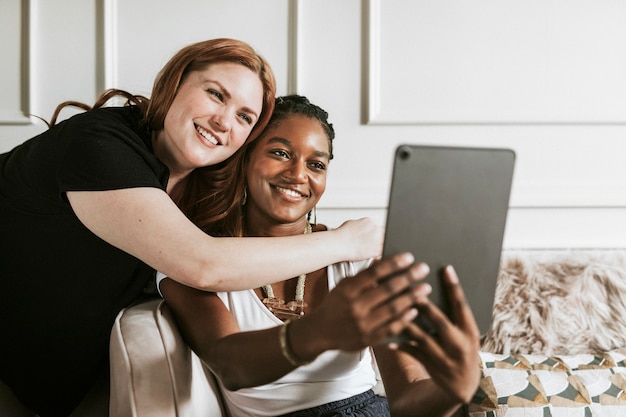 Casal de lésbicas tirando uma selfie com um tablet digital