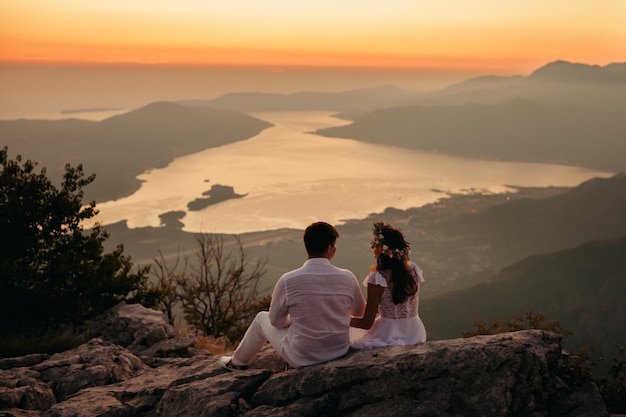 Casal de lua de mel viaja montanhas e vista para o mar. Pôr do sol nas montanhas pitorescas. Baía de Kotor, Montenegro.