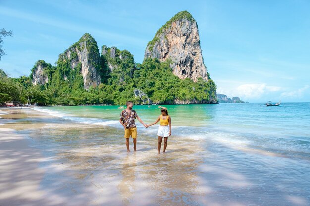 Foto casal de mãos dadas a caminhar na praia de areia