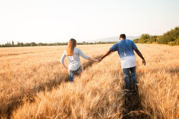 Casal de mãos dadas enquanto caminhava no campo