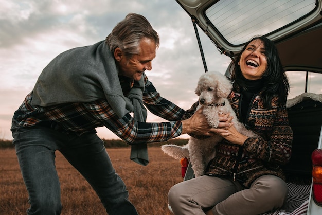 Casal de meia idade com seu cachorro no piquenique