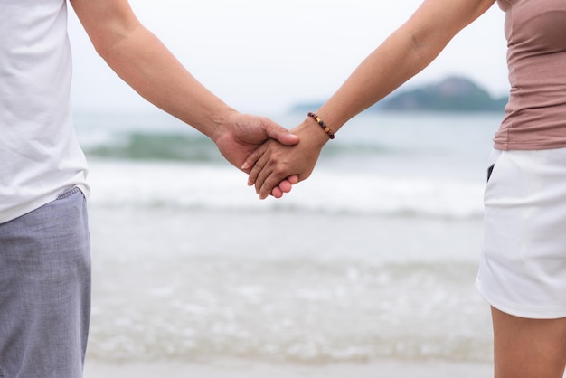 Casal de meia idade de mãos dadas na praia