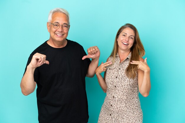 Casal de meia-idade isolado em um fundo azul, orgulhoso e satisfeito com o conceito de amor a si mesmo