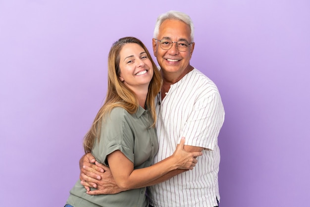 Casal de meia-idade isolado em um fundo roxo se abraçando