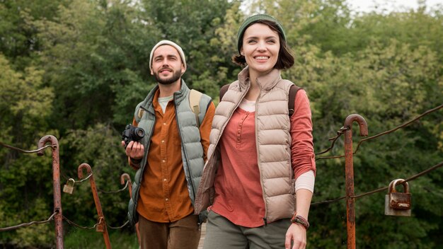 Casal de meio tiro caminhando na ponte de madeira