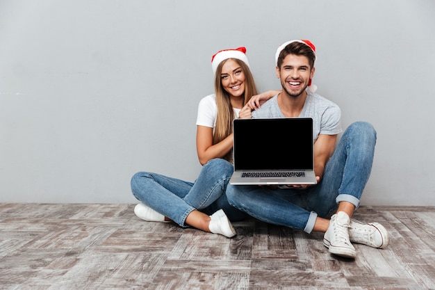 Casal de natal mostrando laptop