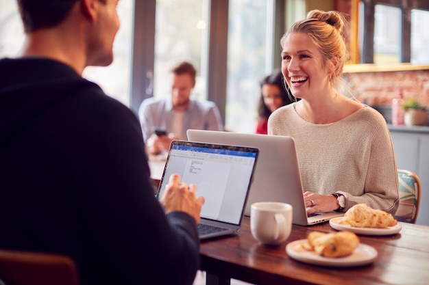 Casal de negócios com laptops tendo reunião informal no café