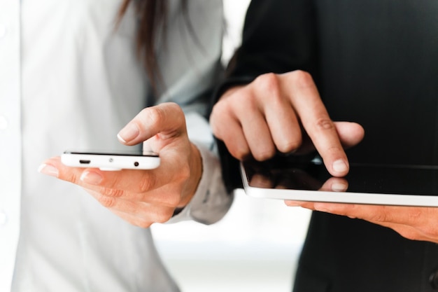 Casal de negócios jovem segurando o gadget no fundo