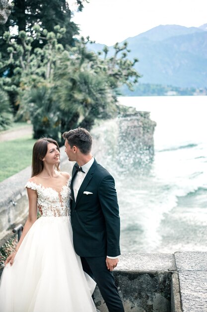 Casal de noivos beijando no fundo de um lago e montanhas