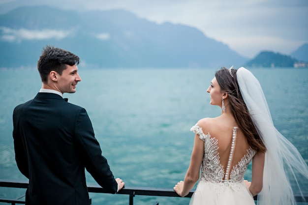 Casal de noivos beijando no fundo de um lago e montanhas