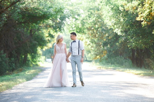 Casal de noivos na natureza em dia de verão. a noiva e o noivo abraçando no casamento.