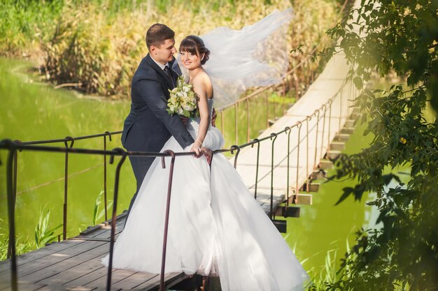 Casal de noivos na ponte sobre o rio no verão