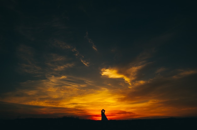 Casal de noivos no fundo do pôr do sol