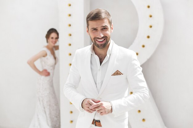 Casal de noivos, noivo e noiva posando em um estúdio branco