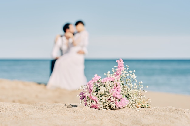 Casal de noivos se beijando na praia