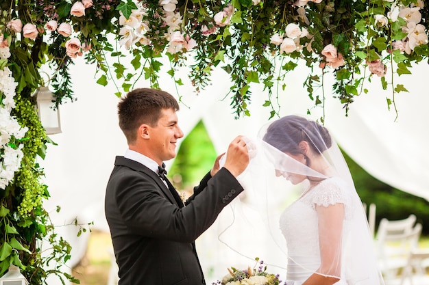 Casal de noivos sob o arco de flores na cerimônia de casamento