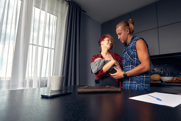 Casal de noivos toma café da manhã juntos em sua nova casa, jovem casal sorrindo enquanto bebe e come na cozinha