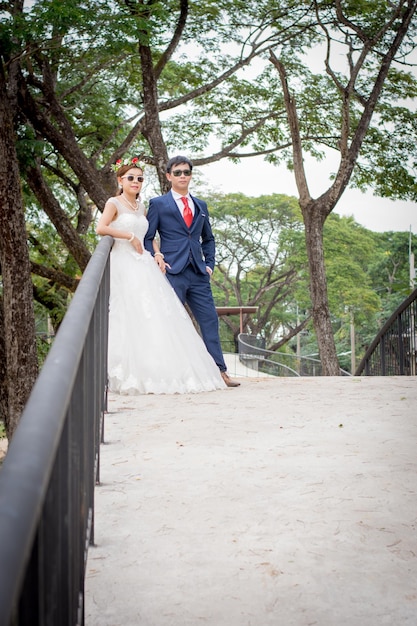 Casal de pé em uma ponte contra árvores