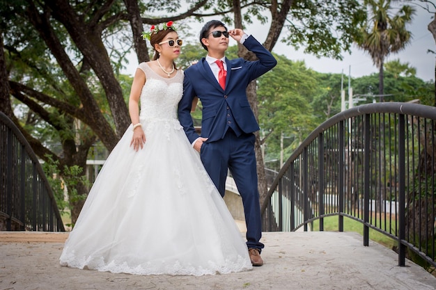 Casal de pé em uma ponte contra árvores