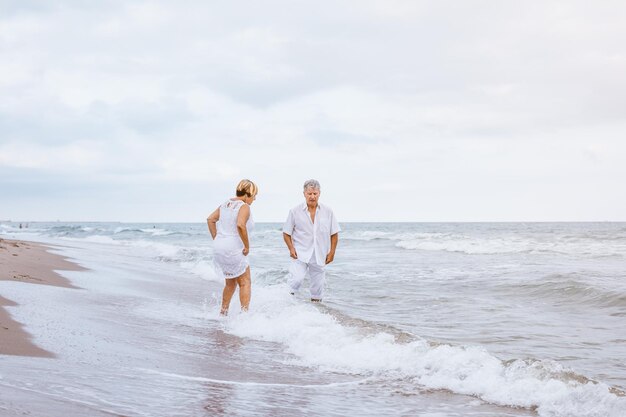 Foto casal de pé na praia com o céu nublado