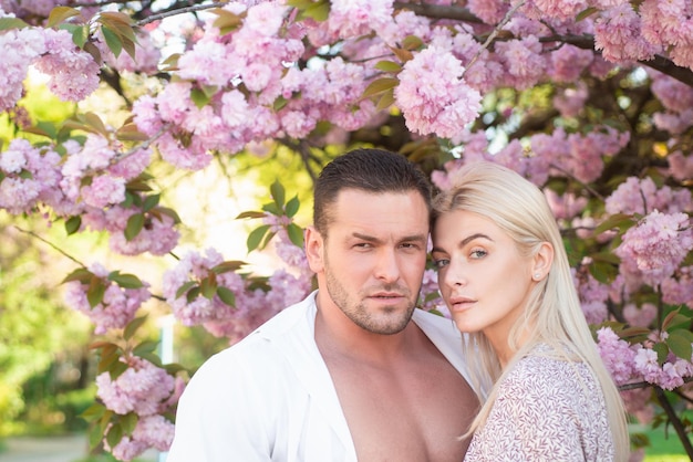 Casal de primavera apaixonado andando no parque sakura e olhando a árvore de flores de cerejeira