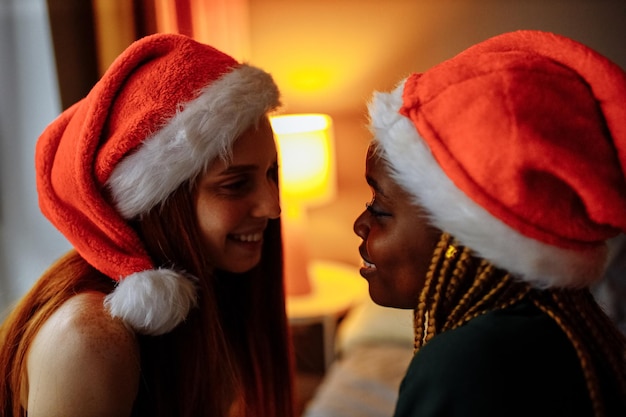 Casal de raça mista com chapéu de papai noel em casa à noite