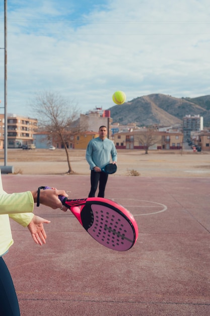 Casal de roupas esportivas joga tênis de remo com raquetes
