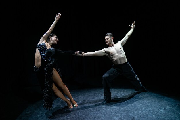 Casal de salão de baile dançando isolado no preto.