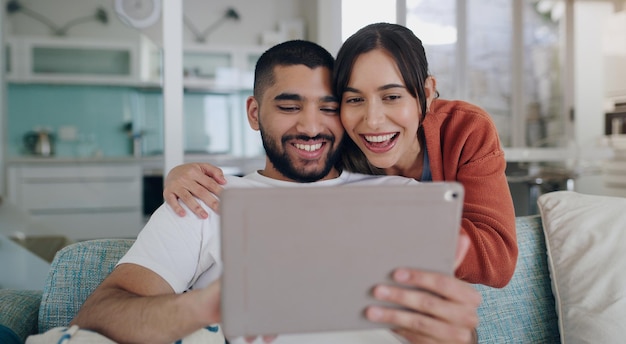 Casal de tablet e sorriso no sofá em casa para site de mídia social e entretenimento online Homem feliz mulher animada e relaxe na assinatura de tecnologia digital ou conexão de streaming na rede