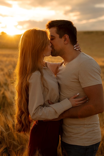 Foto casal de tiro médio beijando ao pôr do sol