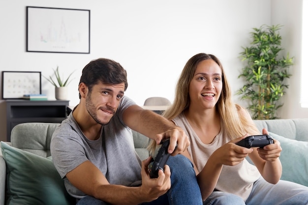 Foto casal de tiro médio com controladores no sofá