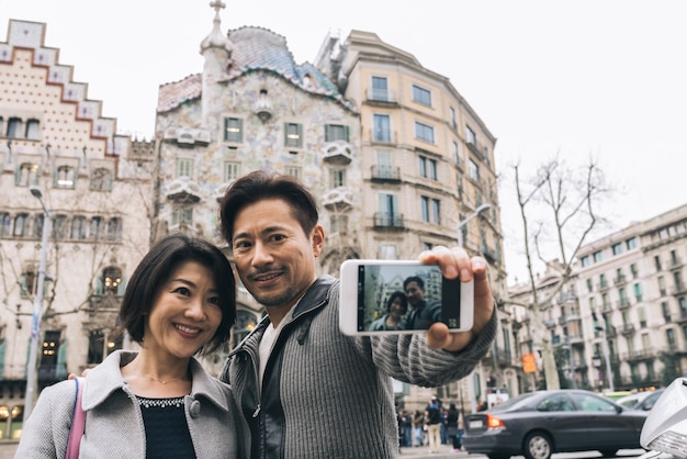 Casal de turistas asiáticos tomando uma selfie com um telefone móvel