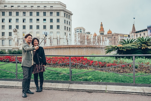 Casal de turistas asiáticos tomando uma selfie no telefone celular