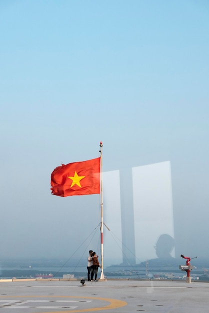 Casal de turistas e bandeira nacional do Vietnã acenando no topo do prédio