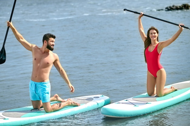 Casal de turistas jovem homem e mulher divertindo-se paddleboarding no mar desfrutando de férias de verão estilo de vida ativo