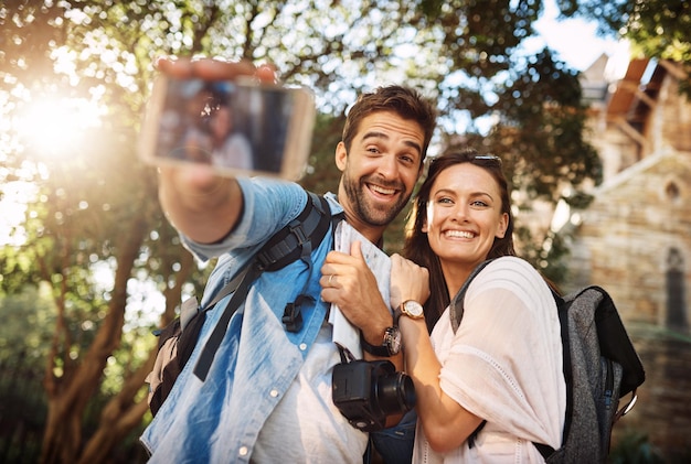 Foto casal de turistas sorri e selfie ao ar livre para viajar em uma cidade para memória de férias ou felicidade homem e mulher felizes tiram fotos nas redes sociais de aventura ou viagem de férias com liberdade, amor e carinho