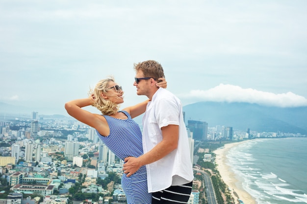 Casal de um homem e uma mulher felizes e lindos juntos no contexto do mar e da cidade em um dia de verão