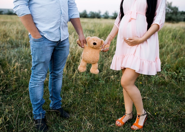 Casal de um homem e uma mulher grávida segurando um ursinho de pelúcia