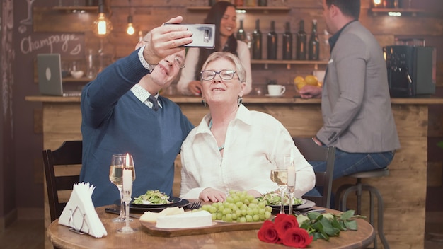 Foto casal de velhos românticos tirando uma selfie durante o almoço em um restaurante. homem e mulher na casa dos sessenta anos. casal de idosos.