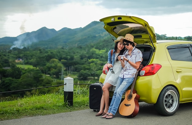 Casal de viajante sentado no hatchback do carro e olhando para a foto