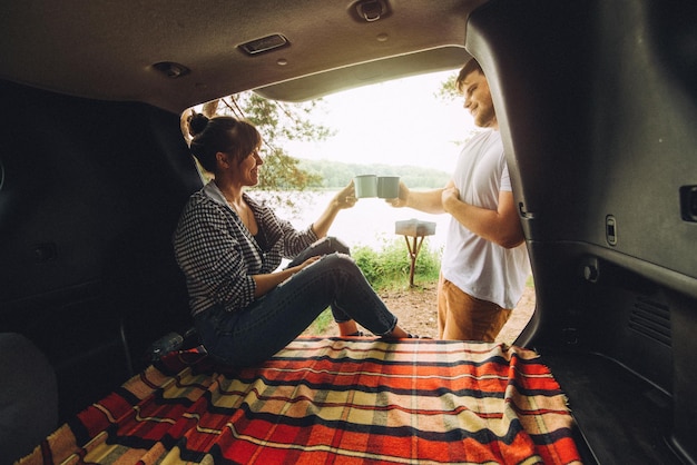 Casal descansando fora do conceito de viagem de carro sentado no porta-malas