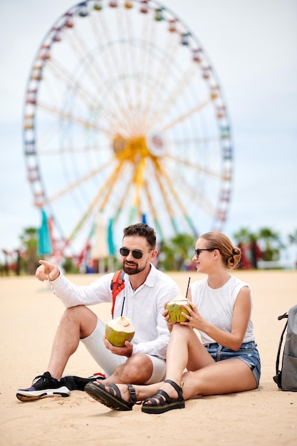 Casal descansando na praia com cocos