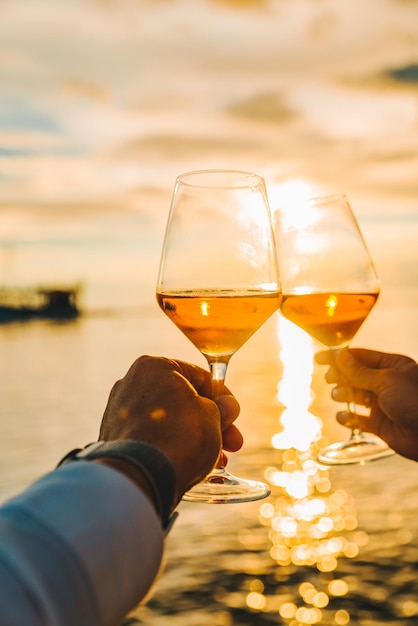 Casal descansando no pôr do sol na praia do mar e bebendo vinho